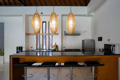 a kitchen with a counter with chairs and lights at Villa Duadewi 4BR in the Heart of Seminyak by Santi Management in Seminyak