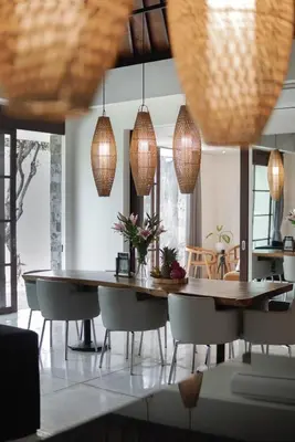 a dining room with a table and chairs and pendant lights at Villa Duadewi 4BR in the Heart of Seminyak by Santi Management in Seminyak