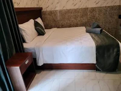 a bedroom with a large bed with a wooden headboard at Tirtasuci House in Kuta