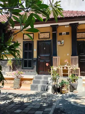 a house with a wooden door and some plants at Tirtasuci House in Kuta