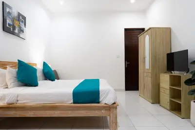 a bedroom with a bed with blue pillows and a television at Nossa Casa Villa in Seminyak