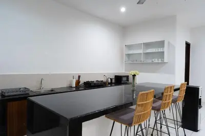 a kitchen with a black counter top and chairs at Nossa Casa Villa in Seminyak