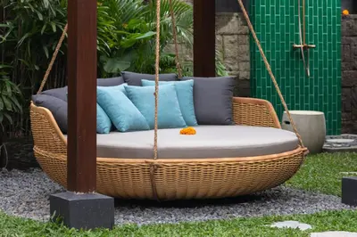 a wicker swing with pillows in a garden at Villa Mahkota Seminyak in Seminyak