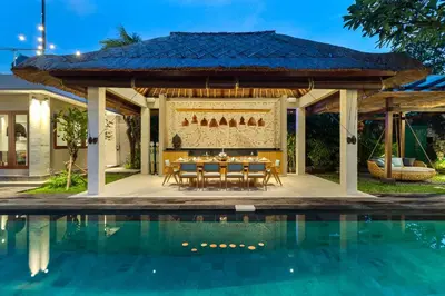a table and chairs under a pavilion next to a pool at Villa Mahkota Seminyak in Seminyak