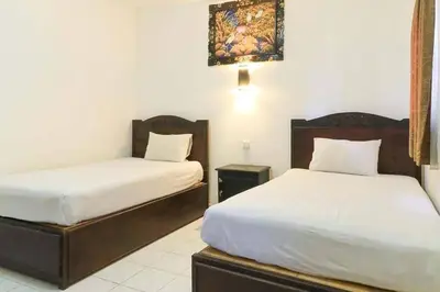a bedroom with two beds and a picture on the wall at SANJAYA HOTEL in Legian