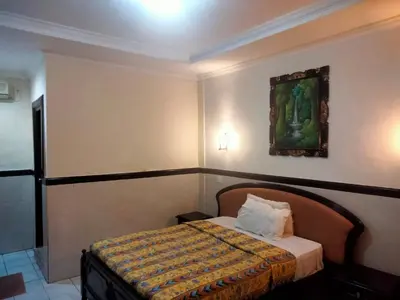 a bedroom with a bed with a painting on the wall at SANJAYA HOTEL in Legian
