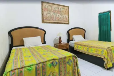 a bedroom with two beds and a night stand with a table at SANJAYA HOTEL in Legian