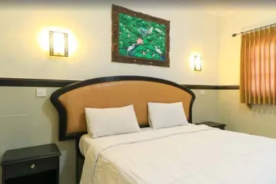 a bedroom with a white bed with a wooden headboard at SANJAYA HOTEL in Legian