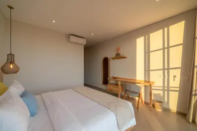 a bedroom with a bed and a desk and a window at Villa LouLou Bali - Brand New Tropical 3BR Villa Next to Canggu in Canggu
