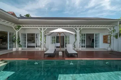 a house with a swimming pool and an umbrella at Blanc Mediterranean: 3BR in Central Canggu in Canggu
