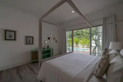 a bedroom with a large bed with a large window at Blanc Mediterranean: 3BR in Central Canggu in Canggu