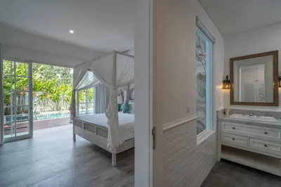 a bedroom with a bed and a bathroom with a sink at Blanc Mediterranean: 3BR in Central Canggu in Canggu