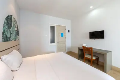 a white bedroom with a bed and a desk at Cove Matahari Senja in Denpasar