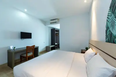 a bedroom with a bed and a desk and a tv at Cove Matahari Senja in Denpasar