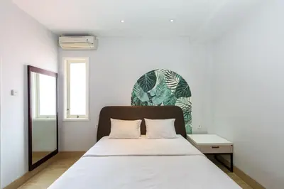 a bedroom with a white bed and a table at Cove Matahari Senja in Denpasar