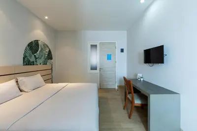 a bedroom with a bed and a desk and a television at Cove Matahari Senja in Denpasar