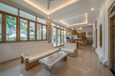 a living room with couches and a table and windows at Villa James Seminyak in Seminyak