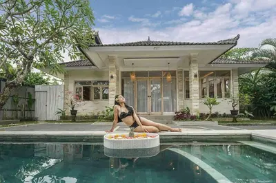 a woman sitting on the edge of a swimming pool at Villa James Seminyak in Seminyak