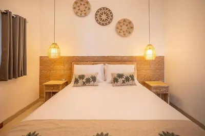 a bedroom with a large white bed with two pendant lights at Villa James Seminyak in Seminyak