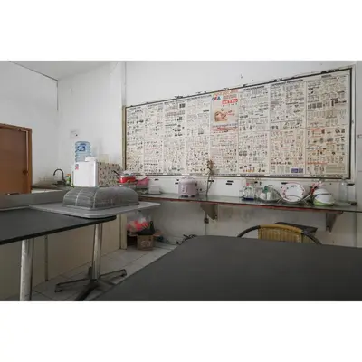 a kitchen with a table and a wall with newspapers at Bunk Bed Bali near Sanur Mitra RedDoorz in Pesanggaran