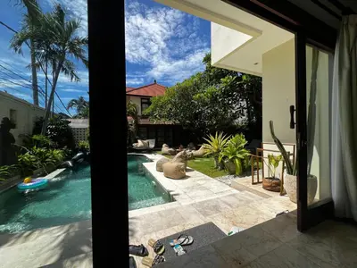 a swimming pool next to a house at Villa Palm Suites Bali in Seminyak