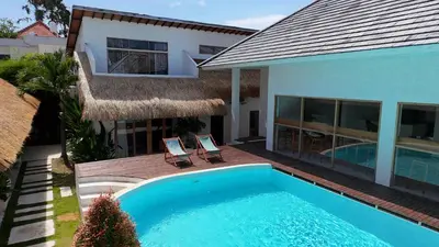 a swimming pool with two chairs and a house at Berawa Village Apartment by Betterplace in Canggu