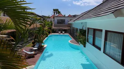 a swimming pool in front of a house at Berawa Village Apartment by Betterplace in Canggu