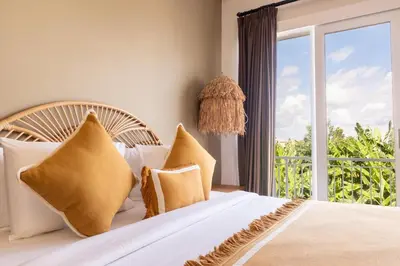 a bedroom with a bed with pillows and a window at Casa Moana Seminyak 3BR Stylish Private Pool Villa in Seminyak