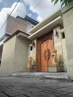 a house with a wooden door with statues on it at Cahaya Residence The Guest House in Kuta