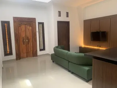a living room with a green couch and a door at Cahaya Residence The Guest House in Kuta