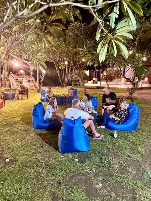 a group of people sitting on blue chairs in the grass at New Mekar Jaya Hotel in Legian