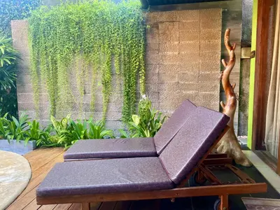 a bench sitting on a deck with a book at Meilds Property Segara Kuta in Kuta