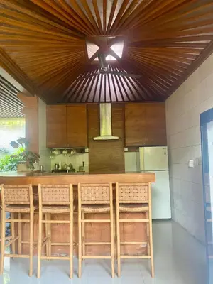 a kitchen with a counter with chairs and a refrigerator at Meilds Property Segara Kuta in Kuta