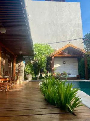 a wooden deck with a pool and a house at Meilds Property Segara Kuta in Kuta