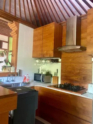 a kitchen with wooden cabinets and a sink and a stove at Meilds Property Segara Kuta in Kuta
