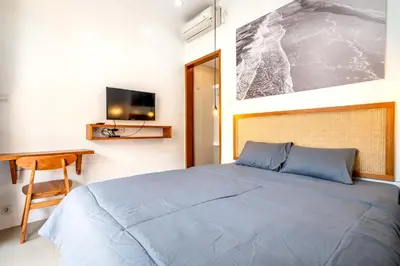 a bedroom with a bed and a desk and a tv at Lumturi House - Centrally Located in Seminyak