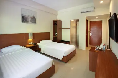 a hotel room with two beds and a television at Bali Chaya Hotel Legian in Legian
