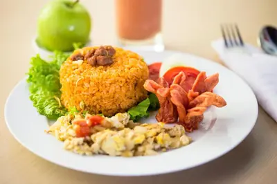 a white plate of food with fried rice and bacon at Bali Chaya Hotel Legian in Legian