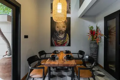 a dining room with a table with chairs and a painting at Villa Zazu in Seminyak