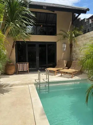 a swimming pool with two chairs and a house at Villa Zazu in Seminyak