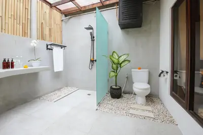 a bathroom with a toilet and a plant in it at Villa Malou in Seminyak