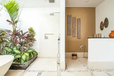 a bathroom with a tub and a shower with plants at Stunning 6 Bedroom Villa Only 400m to the Beach in Canggu