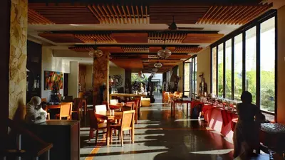 a dining room with tables and chairs and windows at Paragon Hotel Seminyak in Seminyak
