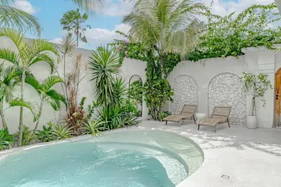 a swimming pool in a garden with two chairs and trees at Villa Lemone 3 by Bali Villa Solutions in Seminyak