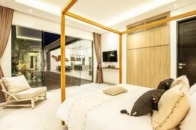 a bedroom with a large bed and a chair at Modern 4 BR Villa 400m to the Beach in Canggu in Canggu