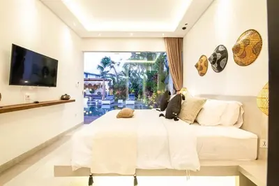 a bedroom with a large white bed and a tv at Modern 4 BR Villa 400m to the Beach in Canggu in Canggu