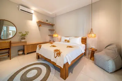 a bedroom with a bed and a chair and a mirror at Villa Della One in Seminyak