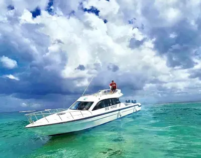 a man standing on the top of a boat in the ocean at Private Yacht Bali to Nusa Penida in Ujung