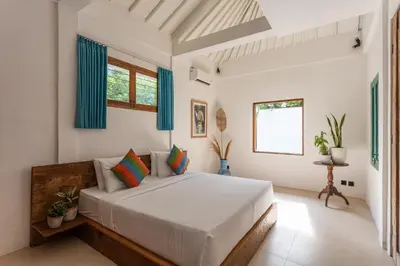 a bedroom with a large white bed with blue curtains at 2 BDR villa, walking distance to Seminyak beach. in Seminyak