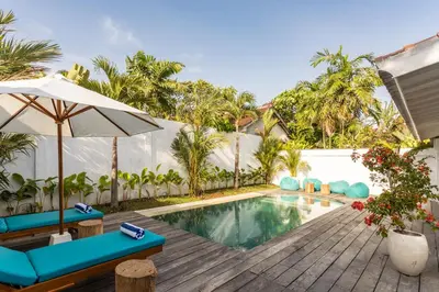 a pool with chairs and an umbrella next to a house at 2 BDR villa, walking distance to Seminyak beach. in Seminyak